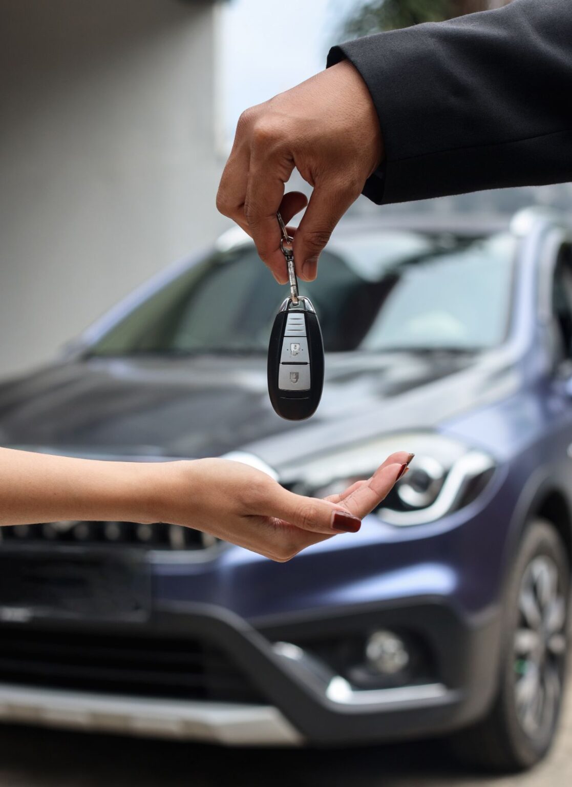 A smiling Le Masé team member handing over a set of car keys to a customer